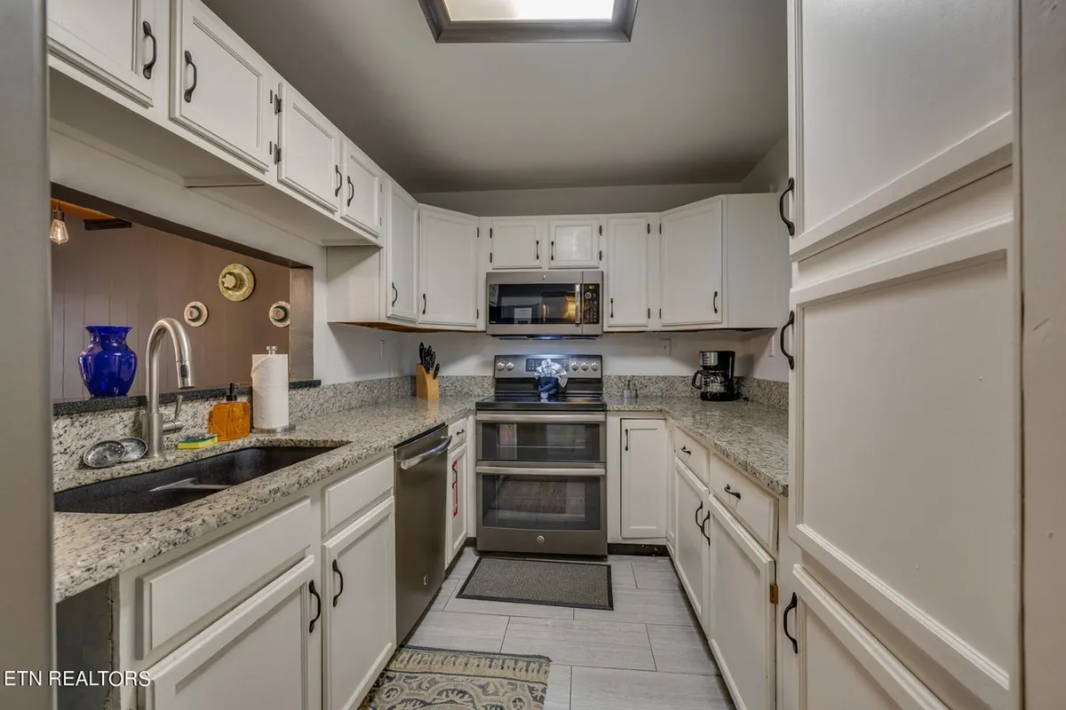 A spacious kitchen island with granite countertops and stainless steel appliances, complemented by a blue vase as a decorative accent. The layout encourages group meal prep and social cooking, with plenty of room to gather and interact.