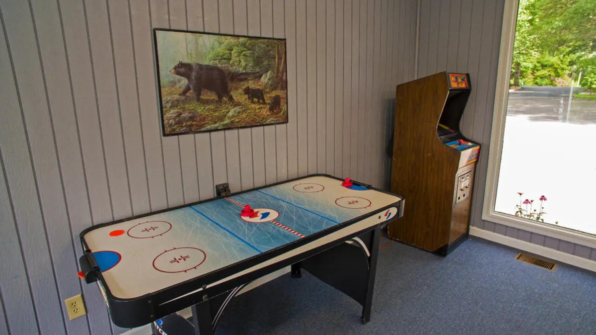 A lively game room equipped with an air hockey table and arcade game, accented by playful decor including a bear painting. The space is designed for fun, socializing, and friendly competition, making it ideal for family game nights and group bonding.